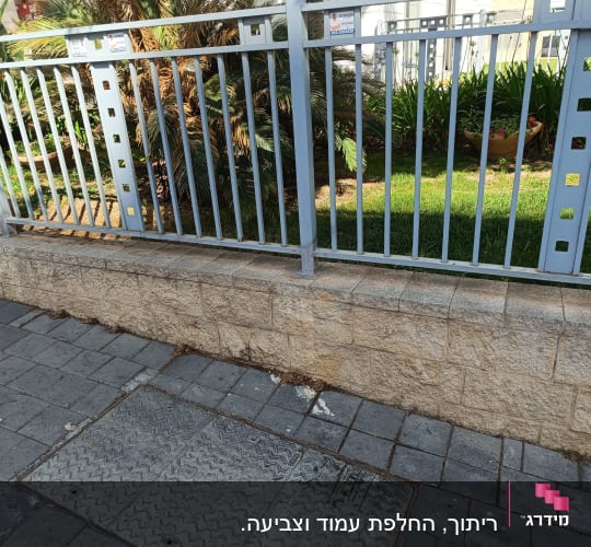 גדר מתכת אפורה עם עמודים מרובעים על מדרכה